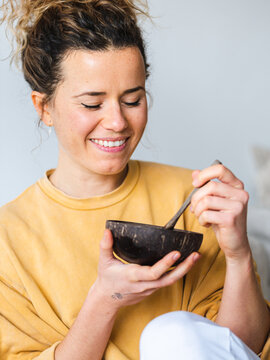 Blonde female with wooden bowl of healthy food at home