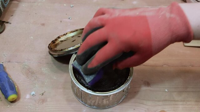 A carpenter processes a wooden part with wax.