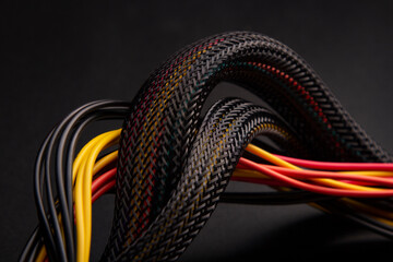 Cable snake skin. Black braided wires in bundle on black background. Braided Sleeving. Data line...