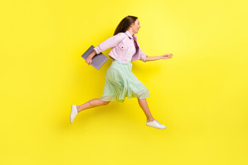 Fototapeta na wymiar Full length body size photo portrait girl in skirt running fast on meeting keeping laptop isolated bright yellow color background