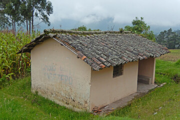 A small tile roofed hut on a farm in the Andes mountains of Ecuador.