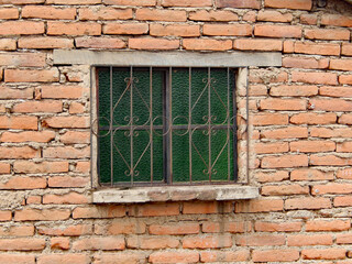 A wrought iron grate covers a window in an adobe brick house in Ecuador.