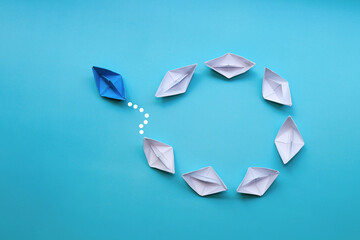 blue paper ship moves differently with with white paper ship.leadership and business concept.