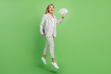 Full body photo of blonde happy woman jump walk hold laptop money wear plaid suit formalwear...