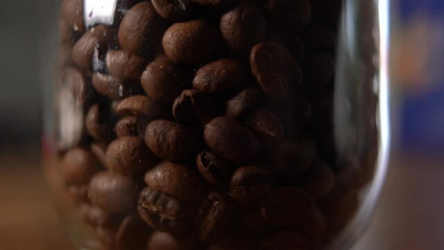 Gros plan de grains de caf&eacute; qui se versent dans un bocal en verre.