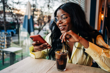 Black woman using smartphone in cafe