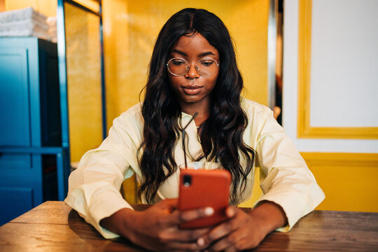 Black woman suing smartphone in cafe