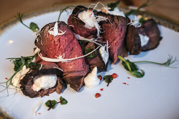 Dish of marbled beef rolls with creamy herb sauce and basil