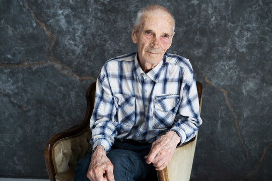 Portrait of elderly man sitting in chair in the room