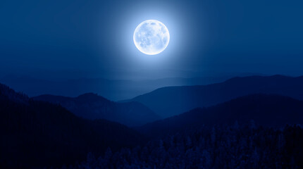 Beautiful landscape with blue misty silhouettes of mountains against super blue moon 
