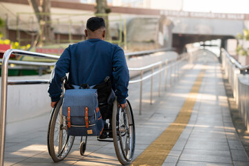 man in wheelchair starting to climb ramp.