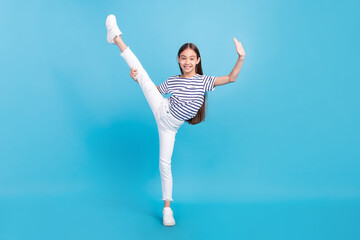 Full length body size careless small girl doing sport excercises smiling isolated pastel blue color background