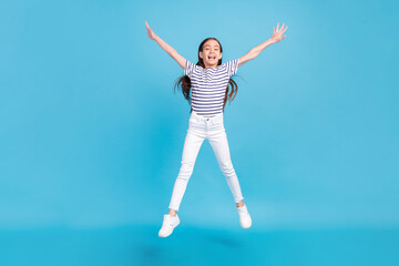 Full length body size careless small girl jumping in casual clothes isolated pastel blue color...