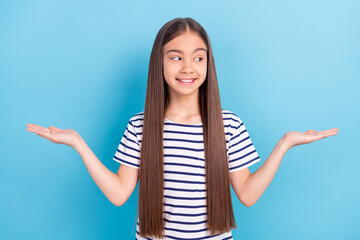Photo portrait little girl in striped shirt smiling keeping empty space on hands comparing isolated...