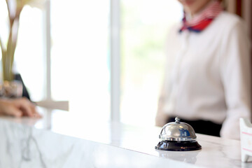 Closeup of silver bell ring on hotel reception service desk with receptionist service customer at...