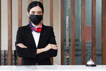 Portrait of young beautiful Asian female receptionist suit wearing face mask to prevent corona...