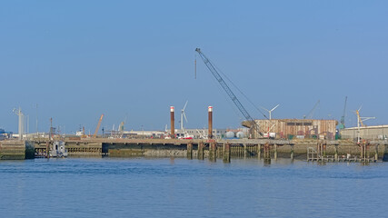 Dock in the industrial harbour of of Boulogne sur mer, Oise, France, with windmills, crane and hangars 
