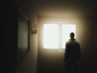 Fototapeta na wymiar man standing in front of window with warm light