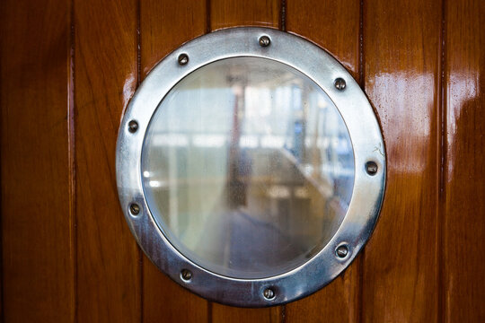 Round porthole on a wooden door,
sea yacht, close up.