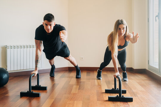 Sporty couple doing push ups with dip stands