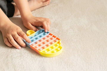 Children's hands play a fashionable sensory anti-stress pop toy. The child plays with a silicone...