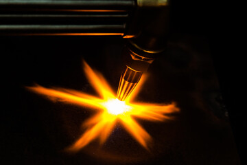 Gas cutting of metal. Gas cutter with copper nozzle with a stream of fire directed at the metal....