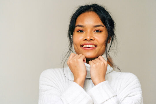 Long-haired brunette Asian woman dressed in a white sweater looking at camera