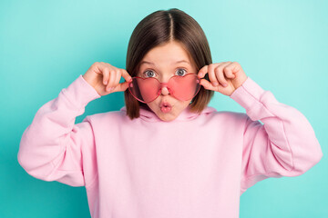 Photo of brunette hairdo impressed little girl hold eyewear wear pink sportswear isolated on teal...