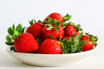 Strawberry berry with green leaf in a plate, isolated on a white background, white table. berries and food