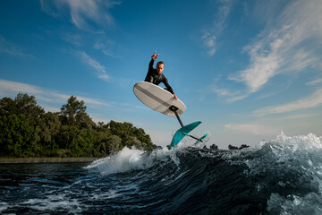 young athletic man skillfully jumping on the wave with foilboard