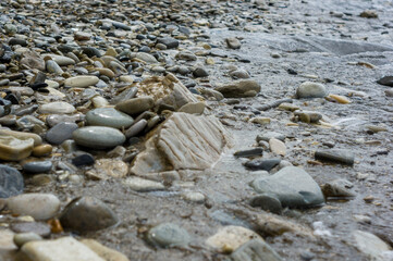 pebble stones on the sea beach, the rolling waves of the sea with foam