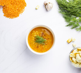 Red lentil soup with ingredients on a light background. Traditional Turkish or Arabic spicy lentil and vegetable soup, healthy vegan food. Top view.