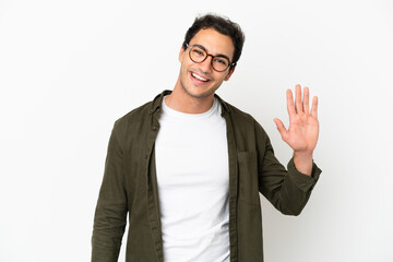 Caucasian handsome man over isolated white background saluting with hand with happy expression