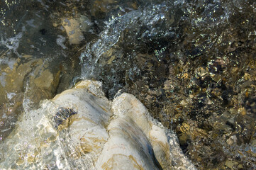 pebble stones on the sea beach, the rolling waves of the sea with foam