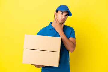 Delivery man over isolated yellow wall having doubts