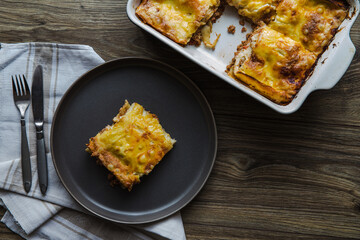 Lasagna on a dark plate with tomato sauce, bechamel sauce and meat. Homemade Italian Lasagna with Tomato Sauce and beef meat. Dark background. Top view.