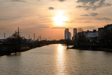Fototapeta premium Evening city landscape with a panorama of high-rise buildings. City sunset by the lake.