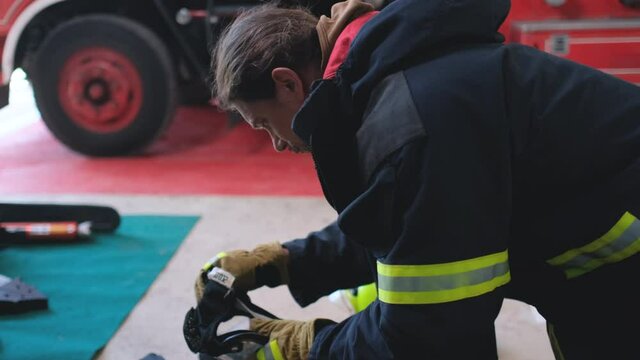 Close up side view of fireman or firefighter check and maintenance equipment for working in area of fireplace office near fire truck. Preparation of good tools support working of staffs concept.