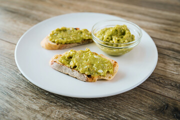 Avocado toasts with egg and shrimp on white plate on wooden table background
closeup.