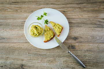 Avocado toasts with egg and shrimp on white plate on wooden table background
closeup.