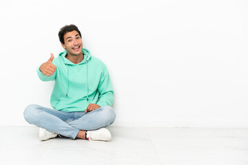 Caucasian handsome man sitting on the floor with thumbs up because something good has happened
