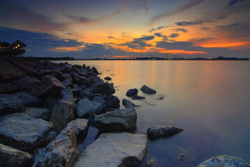 Enjoying the sunset on the marina beach with houses on stilts and rocks in the background