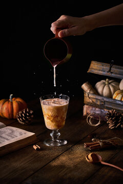 Person pouring milk in glass with latte
