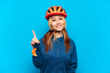 Young cyclist girl isolated on blue background showing and lifting a finger in sign of the best