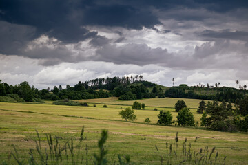 Fototapeta na wymiar Empty field with hills and heavy clouds on background - Czech Republic - Czechia, Europe