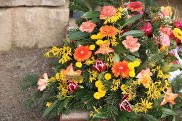 Blumen der Trauer in Orange auf dem Friedhof nach Beerdigung