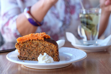 Close-up on woman's hand in coffee shop, enjoying an herbal tea and a slice of carrot cake