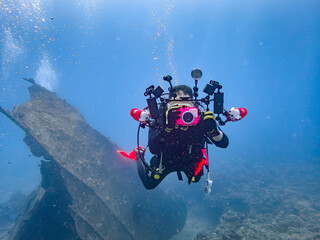 A male diver holding a bright pink waterproof camera underwater