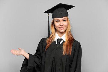 Young university graduate girl over isolated background extending hands to the side for inviting to come