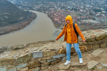 Young girl tourist rejoices posing against the backdrop of an amazing natural landscape. The...